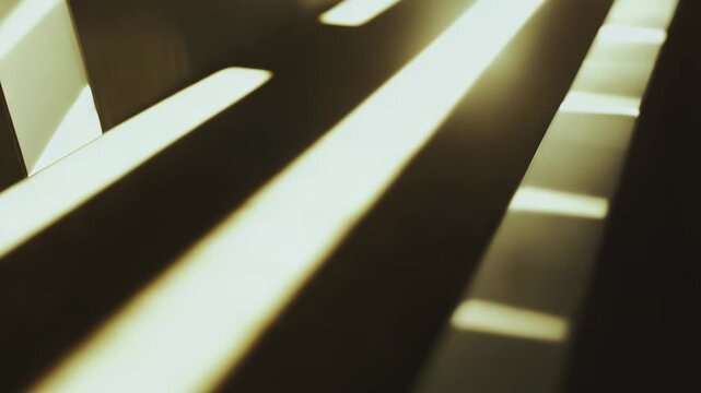 Sunlight creates abstract geometric patterns with strong parallel lines and contrasting shadows, highlighting smooth surfaces and evoking a sense of calm and modern design