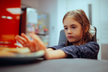 Kid Feeling Full Pushing the Plate of Food Away. Fussy eating child does not want to try the meal her mom prepared