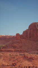 A large rock formation stands prominently in the vast Nevada desert landscape under the scorching sun.
