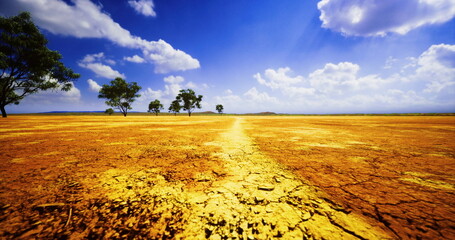 A dry terrain stretches endlessly, revealing cracked earth and a few sparse trees. Fluffy clouds drift across a bright blue sky, illuminating the parched ground. © icetray