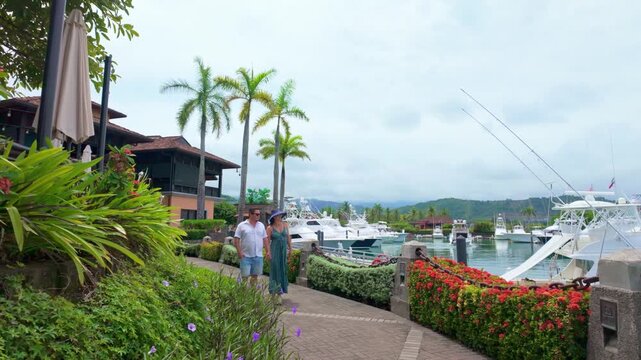 happy couple walking hand-in-hand along a luxury marina at a tropical resort