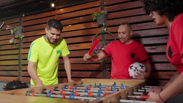 Enthusiastic friends celebrating a goal playing foosball