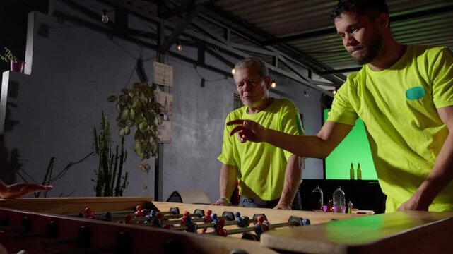 Father and son playing foosball together at night