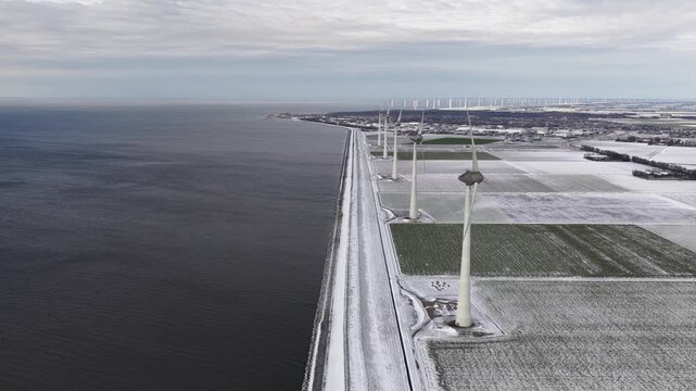 Aerial drone video of the Westermeerwind Wind Farm in winter, located in the IJsselmeer along the Noordoostpolder dikes, showcasing large scale renewable electricity generation.