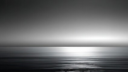 Serene grayscale ocean horizon with bright sun reflection on water