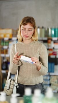 Girl in autumn clothes buys medicinal ointment at a pharmacy. High quality 4k footage