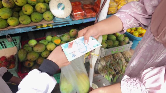 the footage view of a woman taking out rupiah to buy fruit