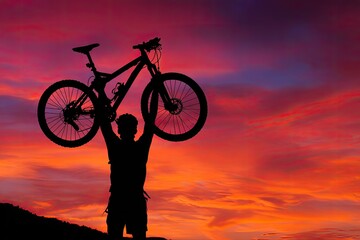 Silhouette of person holding bicycle overhead against vibrant sunset sky