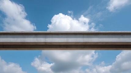 Obraz premium A stark concrete beam structure extends across a bright blue sky dotted with white clouds