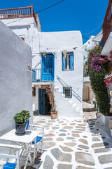 Colorful balconies and stairs in a sunlit alley on a Greek island.