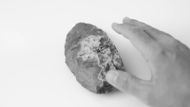 Prehistoric Flint Knife in Hand, Ancient Stone Tool, 4K Video. black and white. slow motion 