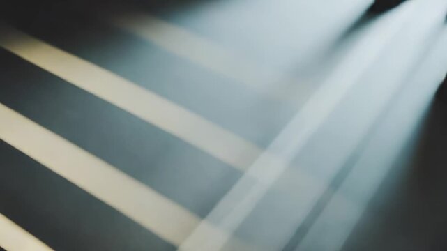 Sunbeams cast parallel stripes of light and shadow across a textured white wall, forming a quiet, geometric morning pattern from an interior window reflection