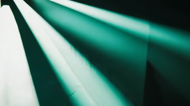 Abstract pattern of bright green light beams creating strong diagonal lines and sharp geometric shadows on a textured surface, forming an intriguing visual composition