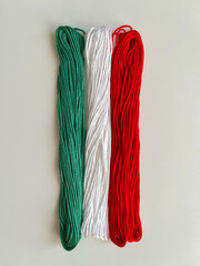 Floss threads of green, white and red colors on a white background.