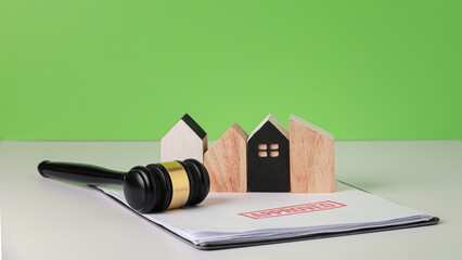 Real estate auction with wooden gavel and model home showing successful housing approval process...