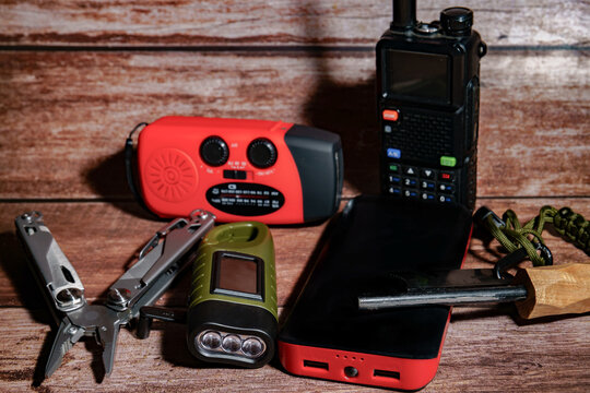 Emergency kit containing personal safety equipment like radio, walkie talkie, multitool, flashlight, power bank, and fire starter