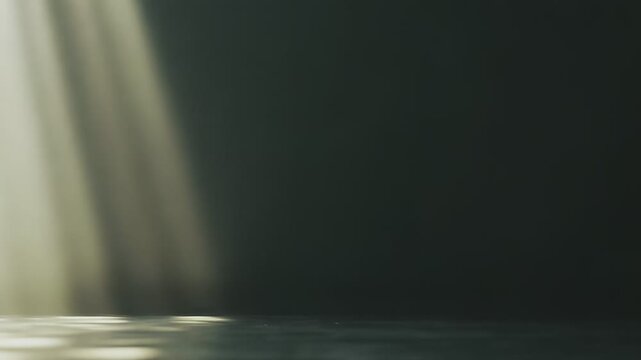 Golden light rays shining through a dark, empty space, creating bright patches on a textured floor, evoking concepts of hope, spirituality, and divine presence