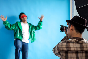 Photographer Capturing Vibrant Model in Studio with Bright Blue Background
