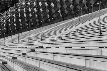 Empty modern stadium seating with concrete steps and geometric roof structure, minimalist architectural perspective © blackday