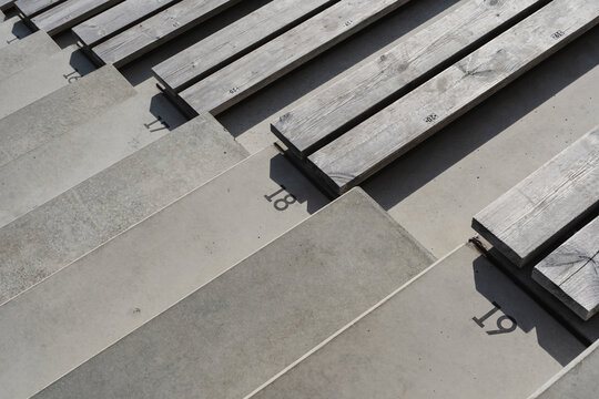 Empty stadium seating with wooden benches and numbered concrete steps