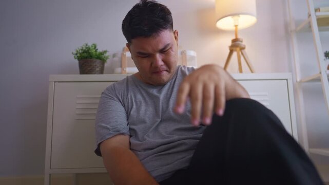 Depressed Asian plus-size man feel upset while sitting alone on floor. 