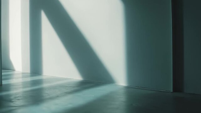 Minimalist interior space showing abstract light patterns and strong dark shadows from sunlight entering an architectural corridor, creating a serene, calm atmosphere