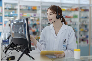 Female pharmacist wearing headset using computer to consult patients online. Healthcare...