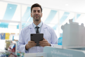 Confident pharmacist holding digital tablet while managing medical information. Male healthcare...