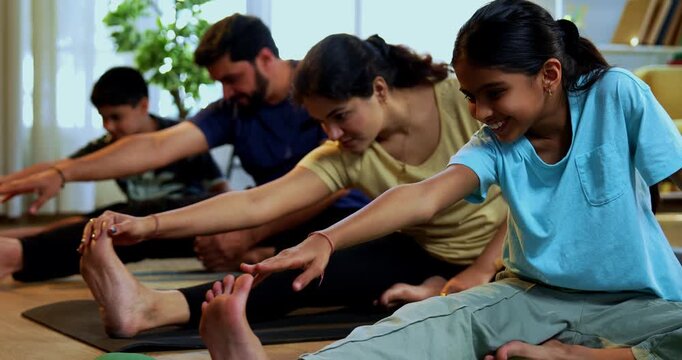 Indian family doing yog asana at home practicing janu shirasana seated head to knee yoga together indoors during calm morning hours inside a modern lavish living space promoting healthy lifestyle