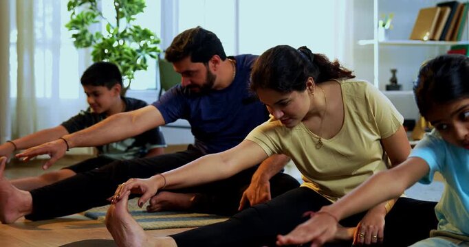 Indian family doing yog asana at home practicing janu shirasana seated head to knee yoga together indoors during calm morning hours inside a modern lavish living space promoting healthy lifestyle