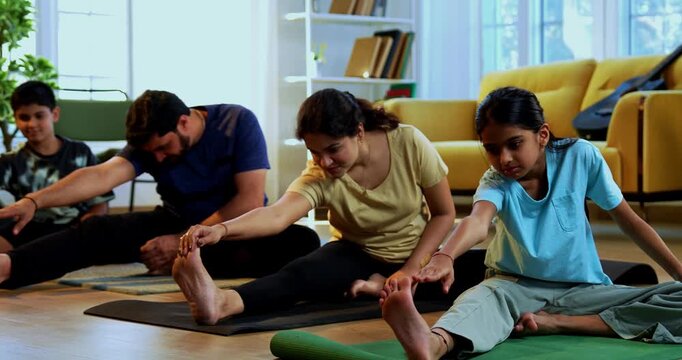 Indian family doing yog asana at home practicing janu shirasana seated head to knee yoga together indoors during calm morning hours inside a modern lavish living space promoting healthy lifestyle