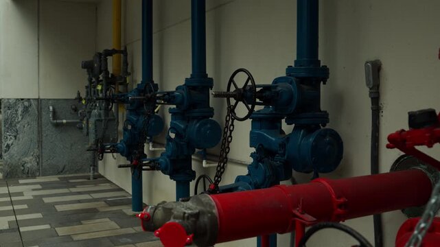 Industrial utility area featuring fire suppression pipes, control valves, pressure gauges, and color-coded plumbing infrastructure.