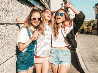 Portrait of three young beautiful smiling hipsters in trendy summer clothes. Sexy carefree women...
