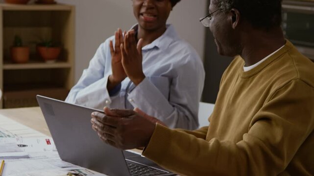 Close up shot of Black senior man using laptop and closing screen celebrating finishing tasks with young woman