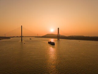 Fototapeta premium River landscape with bridge and cargo ship at sunset in Wuhan China