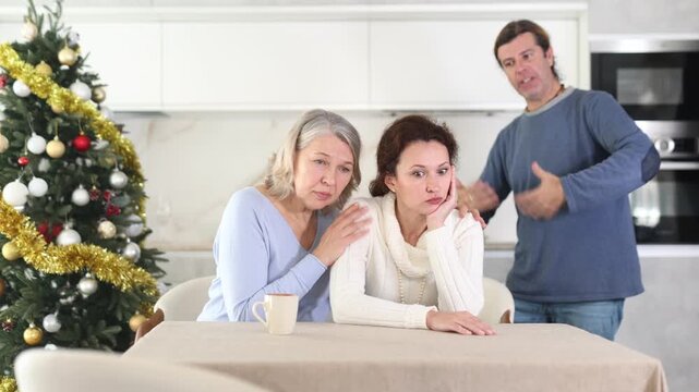 On Christmas Eve woman sits near daughter and comforts during quarrel with husband. Mother calms upset daughter takes side of woman in altercation with brother. Man is outraged by girlfriend behavior 
