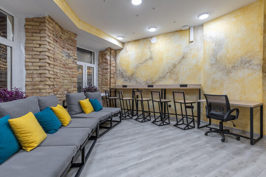 Spacious hostel lounge with long grey sofa and bar counter at night