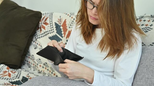 Asian woman having stress while she try to finding money in her empty wallet. Having financial problems means being unable to pay debts over the short or long term.