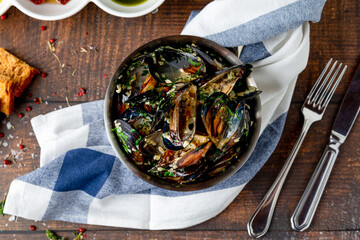 Italian mussels cooked with herbs and sauce in black bowl