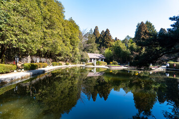 Obraz premium A serene lake reflects trees and a traditional building in Lushan Mountain, Jiangxi China
