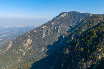 Fototapeta premium Majestic mountain slopes covered in lush green trees rise dramatically in Lushan Mountain, Jiangxi China