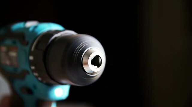 Close-up view spinning chuck blue cordless drill. Small light illuminates work area. Power tool for construction home improvement repair. Focus functionality precision durability.