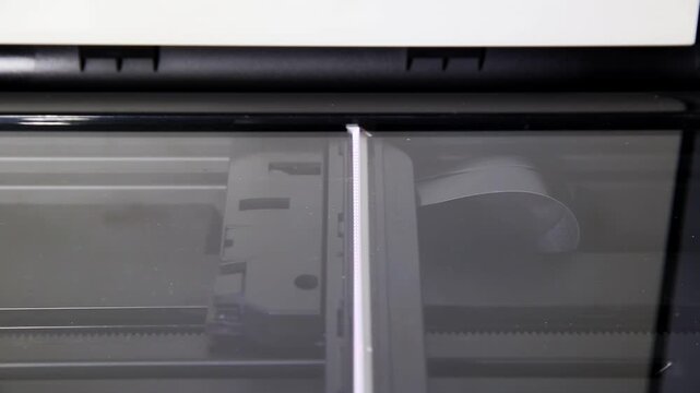 Close-up internal view of flatbed scanner operation. Scanning head moves across glass plate, illuminating document area. Sensor array captures image data