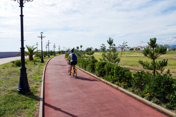 Cyclist on red trail in Sochi Olympic Park with palm trees and lamps