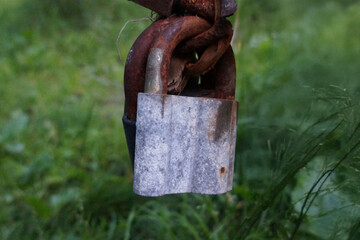 Old rusty padlock hanging in overgrown green grass