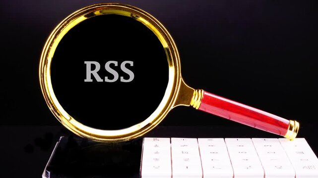 A golden magnifying glass with a red handle rests on a black background, gradually revealing the letters RSS Rich Site Summary