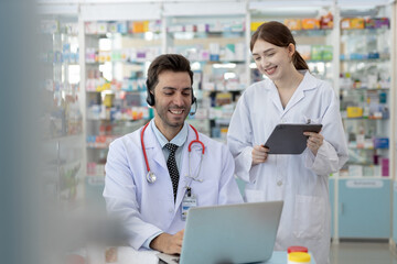 Male and female pharmacists working together using laptop in pharmacy. Healthcare professionals...
