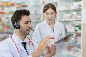 Pharmacists discussing inspecting medicine bottle together. Male and female healthcare...