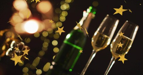 Obraz premium Showing two clear champagne flutes bubbly on party table with green bottle, gold stars, copy space