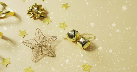Sitting wire star ornament sparkling on pale gold tabletop, with jingle bells and bow, copy space